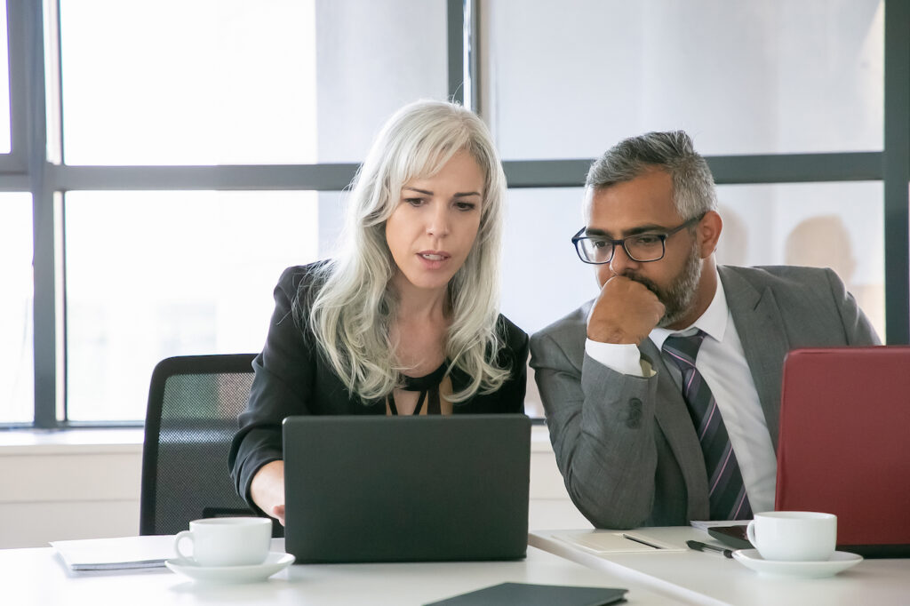 business woman and man discussing over laptop